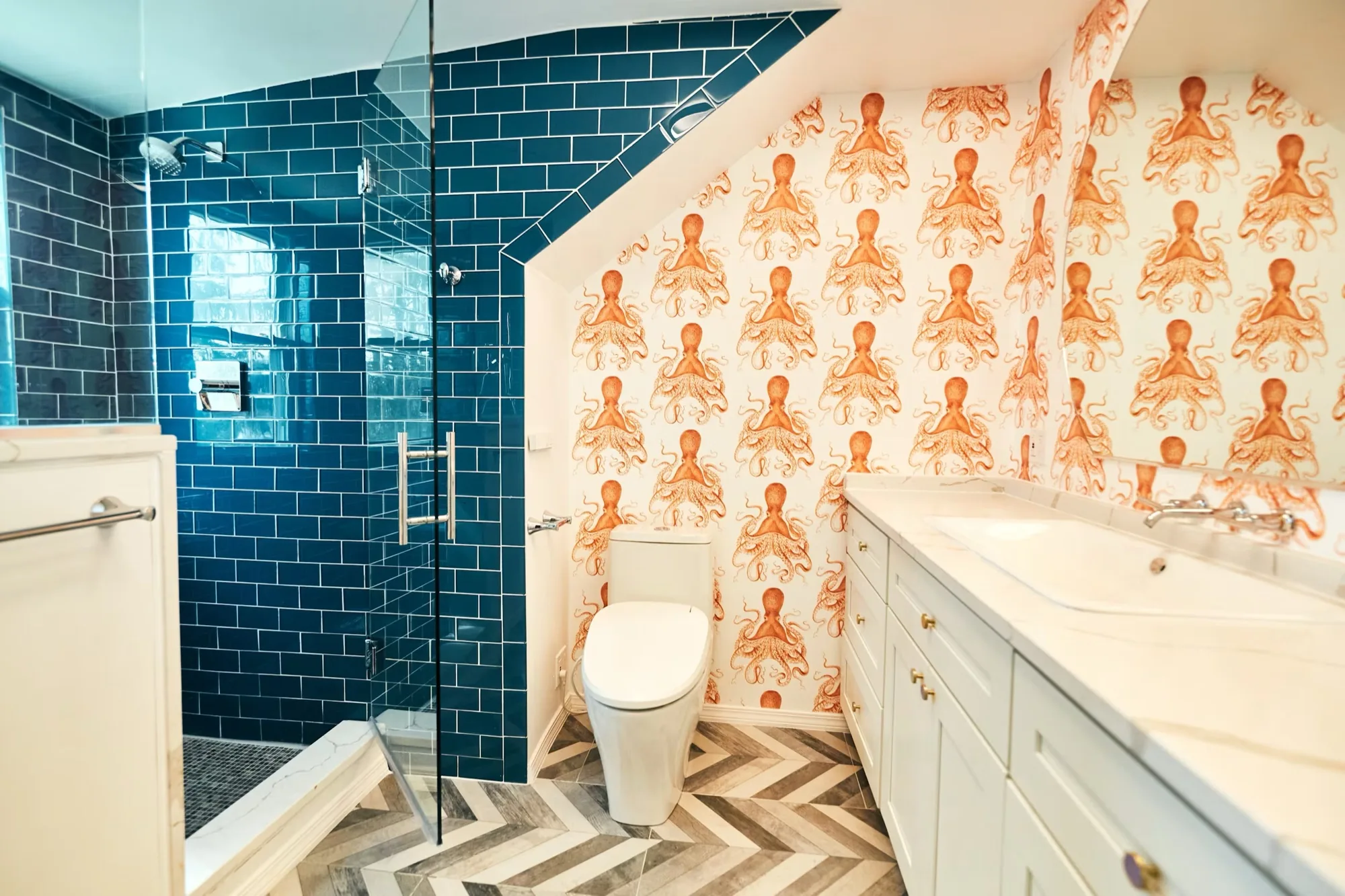 Powder room with orange octopus wallpaper, an ocean blue glass tile shower and a herringbone floor