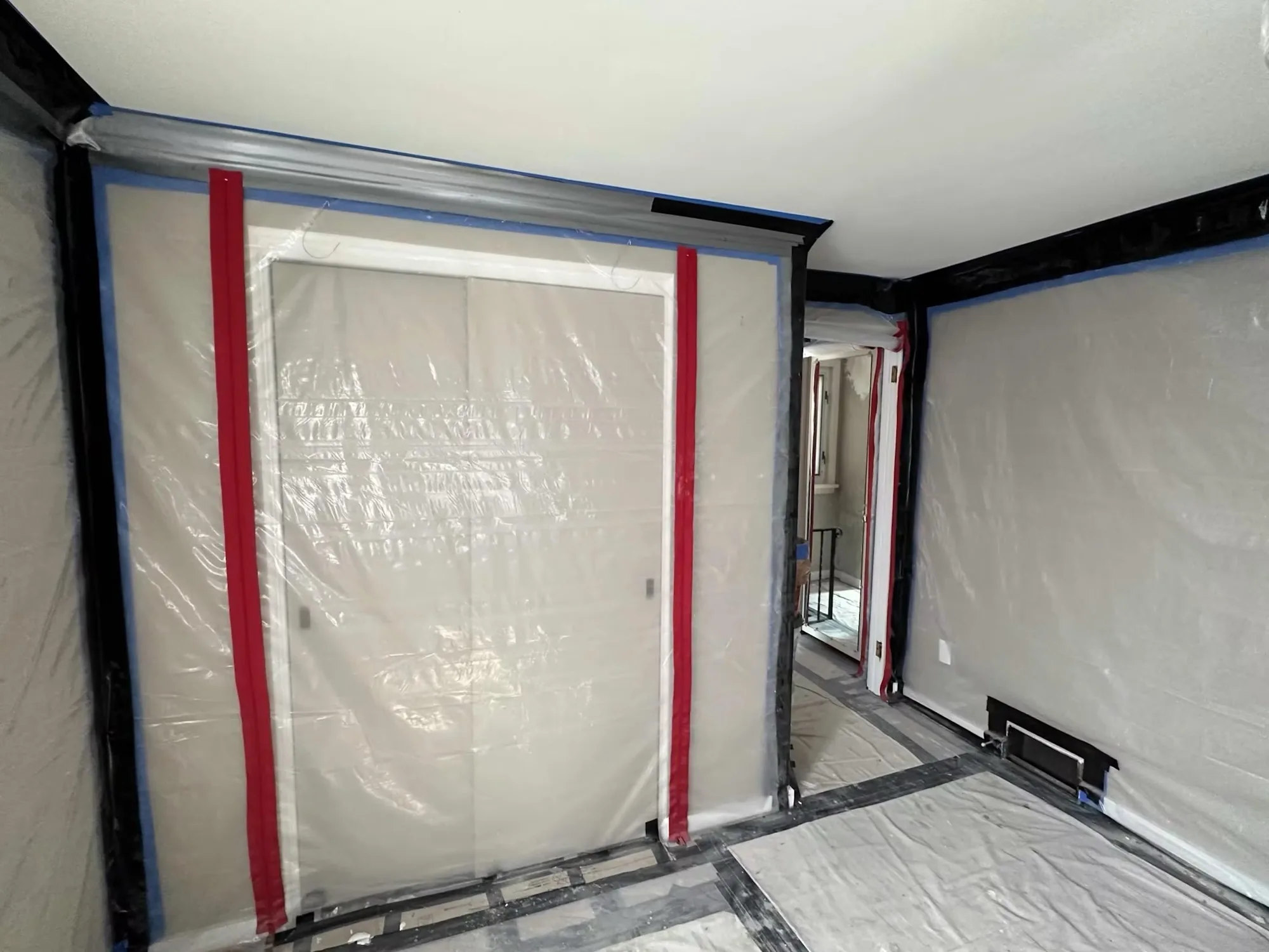 A zippered plastic containment wall built across a doorway inside a home