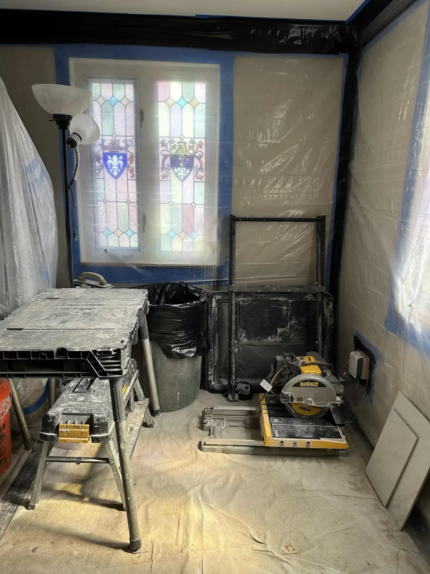 Interior work area with covered floors, a cut station and a stained glass window masked off